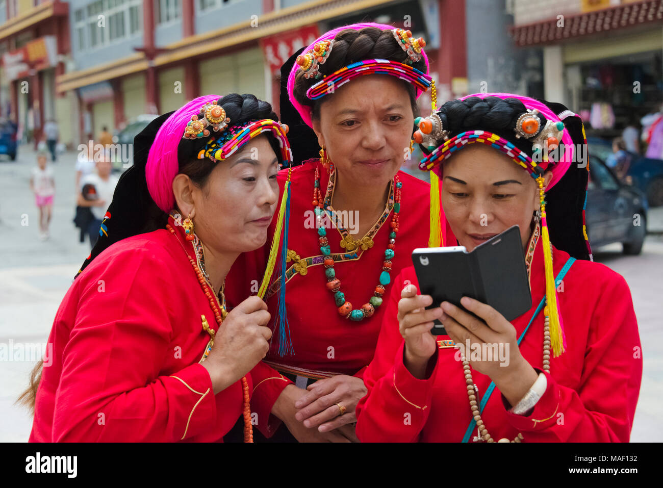Il Tibetano donna in abiti tradizionali a guardare il telefono cellulare Danba, Danba County, Garze tibetano prefettura autonoma, western Sichuan, Cina Foto Stock