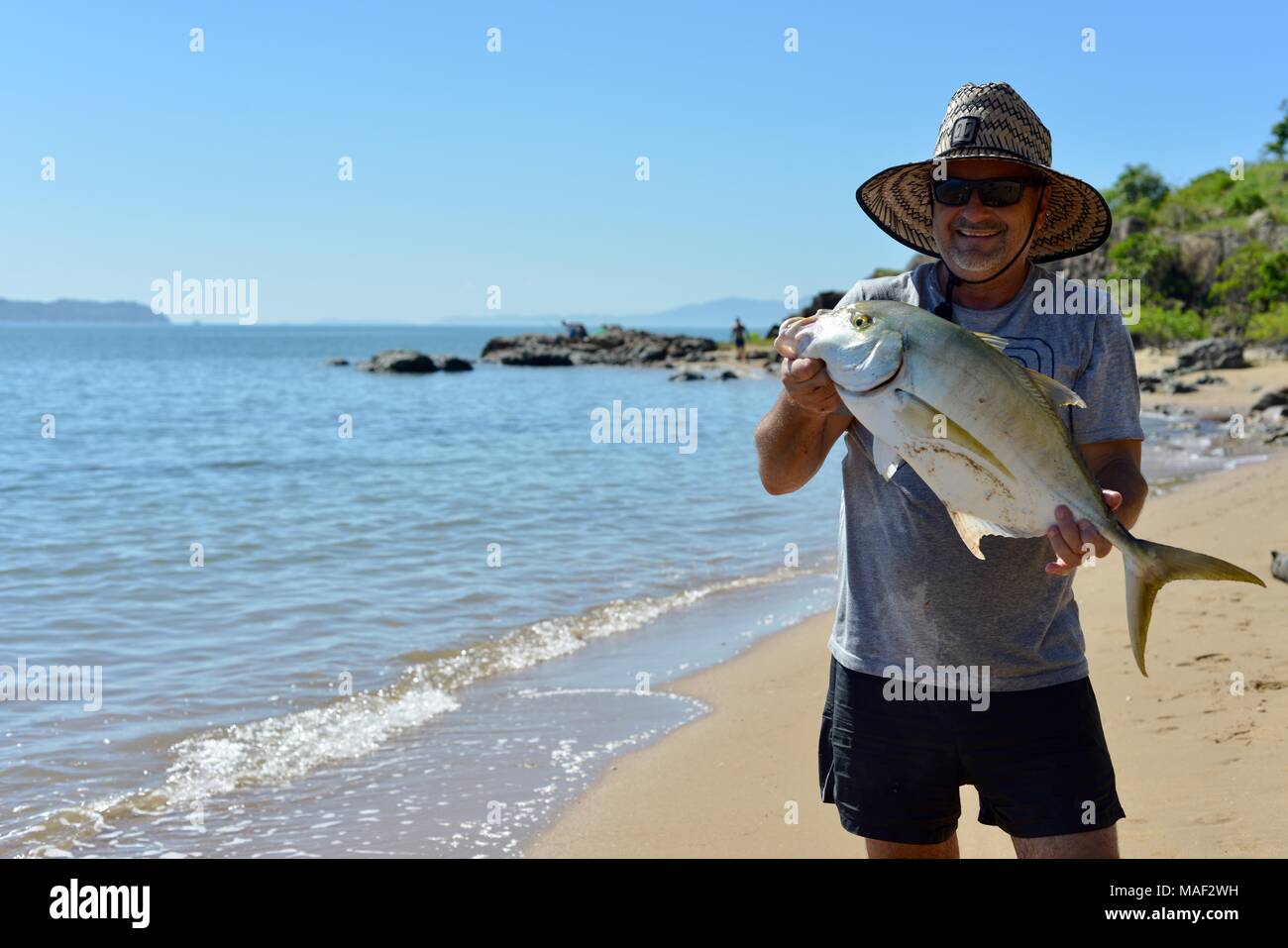 Orgoglioso pescatore con il pescato del giorno, probabilmente carangidi giganti (Caranx ignobilis) Shelly Cove trail a Cape Pallarenda Conservation Park Foto Stock