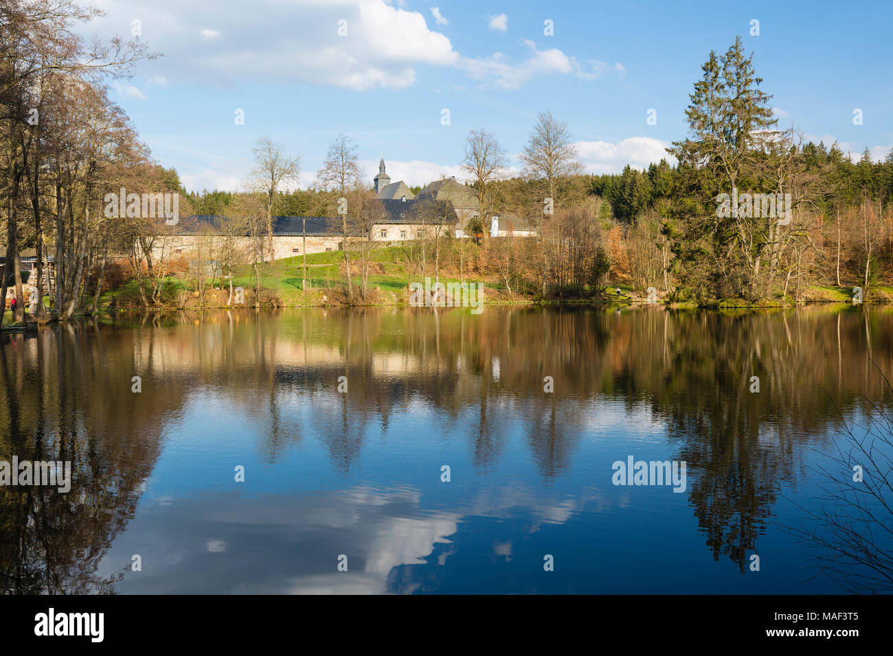 Il monastero Reichenstein vicino Monschau, Germania in primavera con la riflessione in un lago. Foto Stock