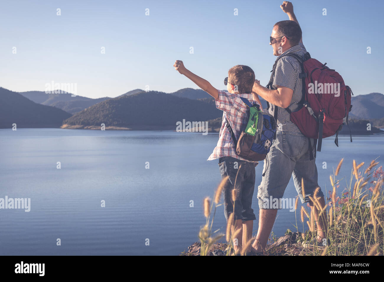 Felice il padre e il figlio in piedi vicino a un lago al giorno. Concetto di famiglia amichevole. Foto Stock