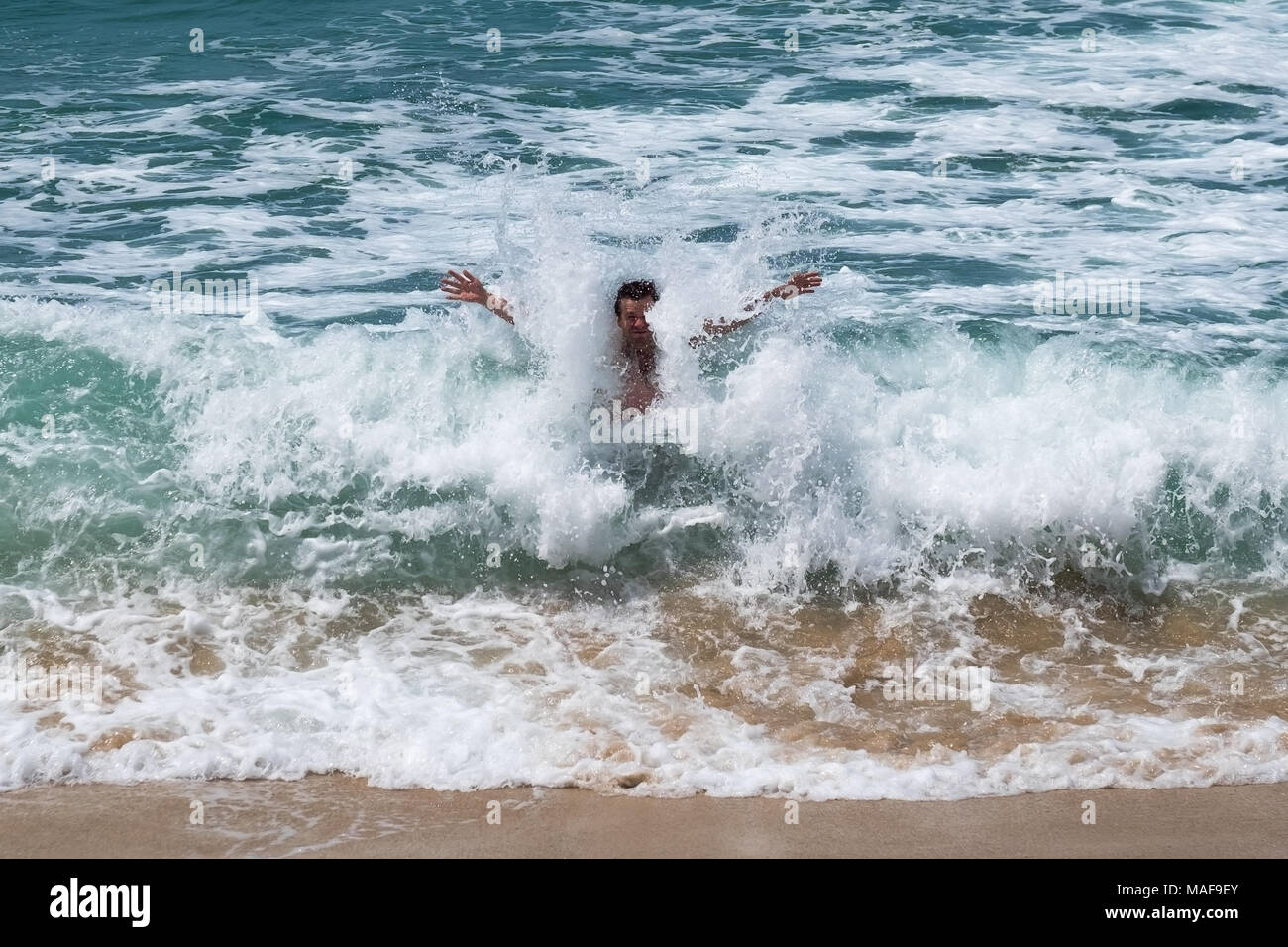 Uomo caucasico saltando sulle alte onde in Oceano Indiano dello Sri Lanka Foto Stock