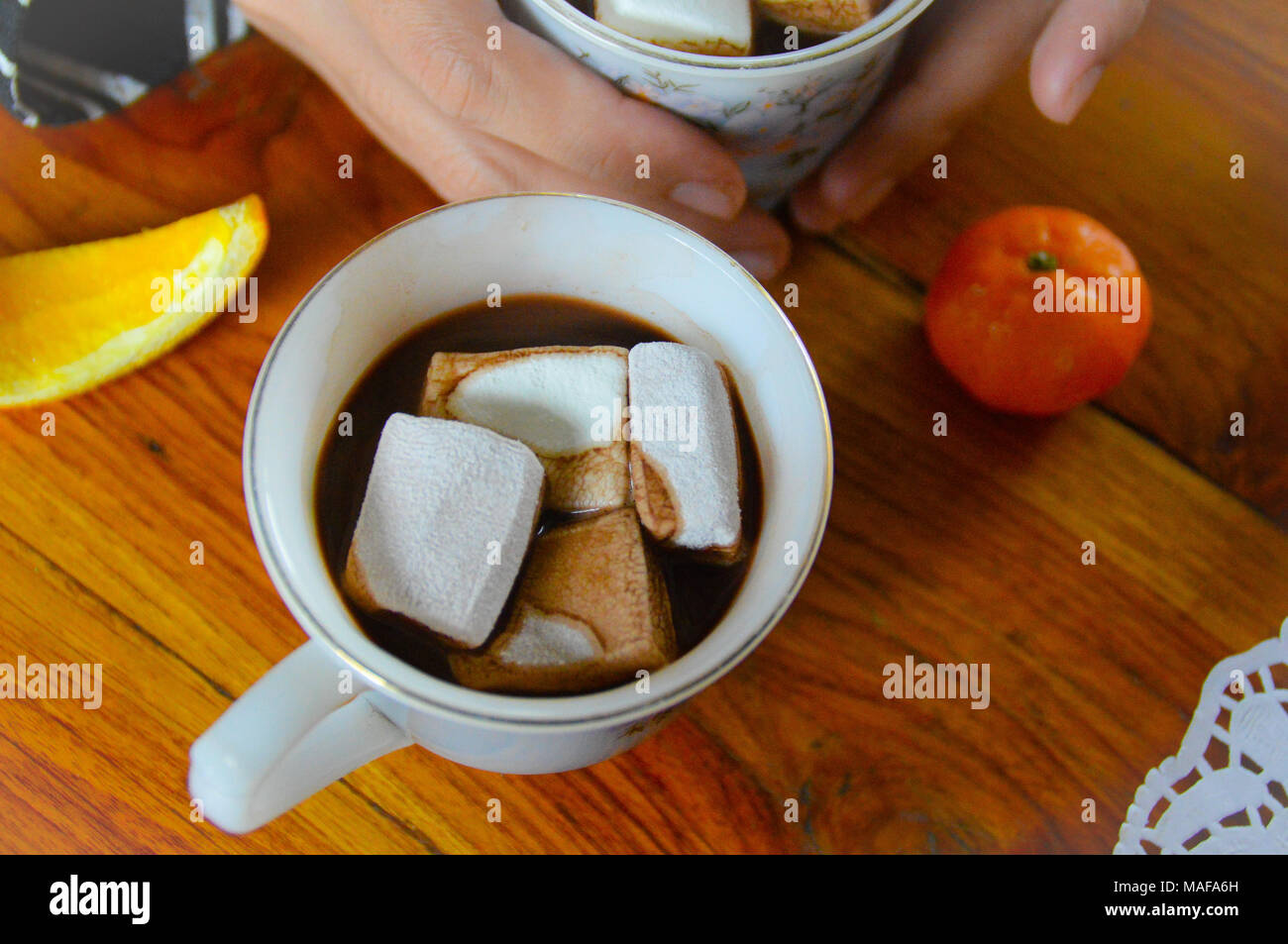 Condivisione di una tazza di cioccolata calda a bere con marshmallows in una fredda mattina presto Foto Stock