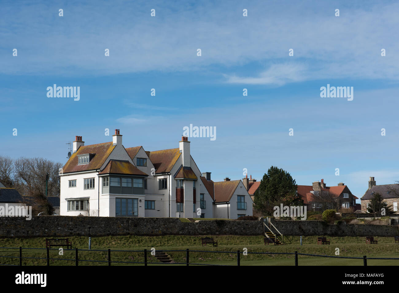 Case sul mare con tetti a spiovente e giardini sotto un cielo blu sulla costa del Northumberland, in Inghilterra Foto Stock