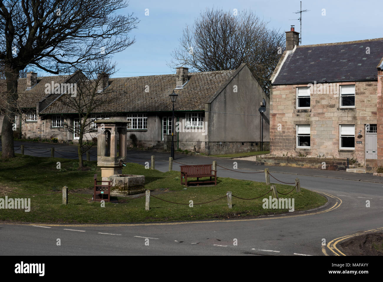 Verde villaggio con cottage in pietra e memoriale di guerra in una strada tranquilla nel Northumberland, Inghilterra Foto Stock