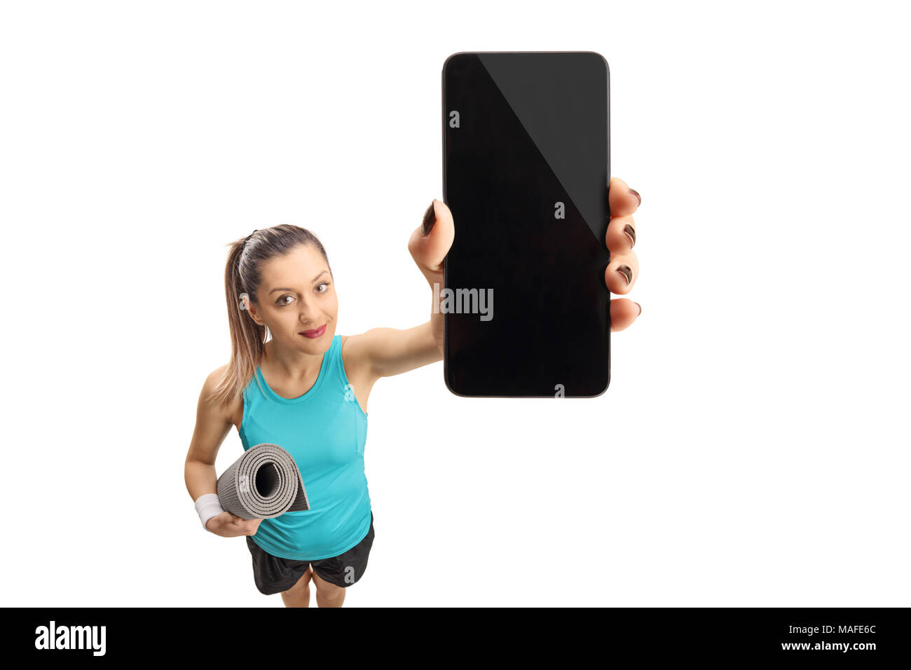 Donna Fitness con un tappetino di esercizio che mostra un telefono isolato su sfondo bianco Foto Stock
