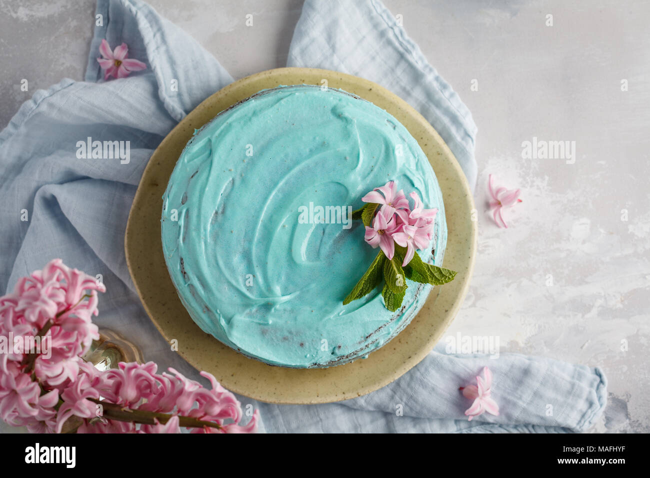 Elegante blu torta con fiori e foglie di menta. Copia spazio, vista dall'alto. Foto Stock