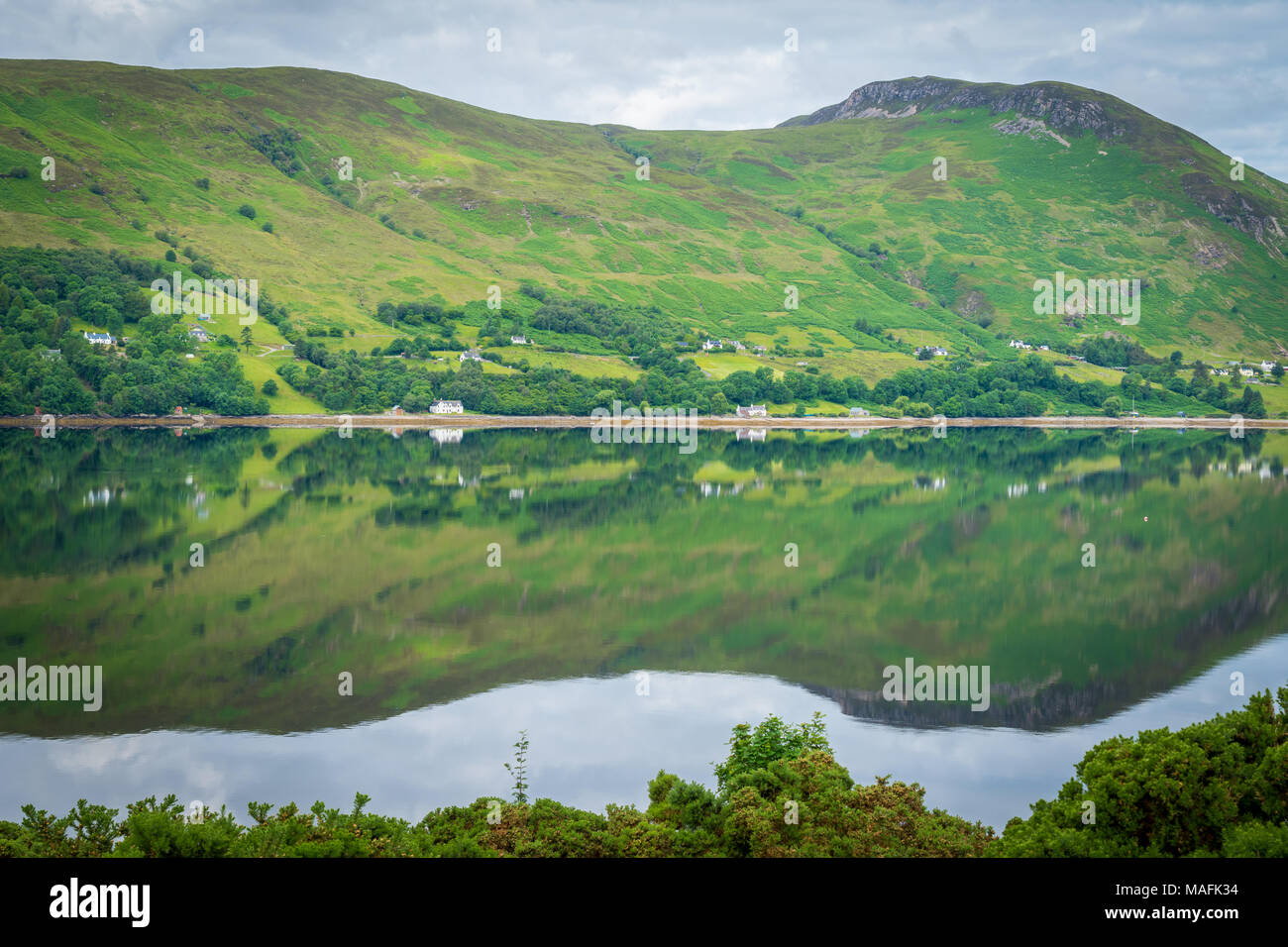 Specchio simili riflessioni sul Loch scopa in una mattina nuvoloso Foto Stock
