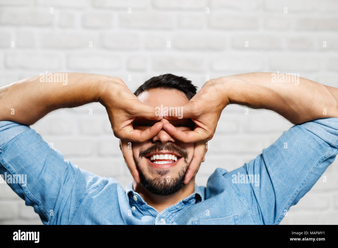 Ritratto di felice italiano uomo sorridente. Guy guardando la fotocamera e fare divertente gesti con le mani e le dita Foto Stock