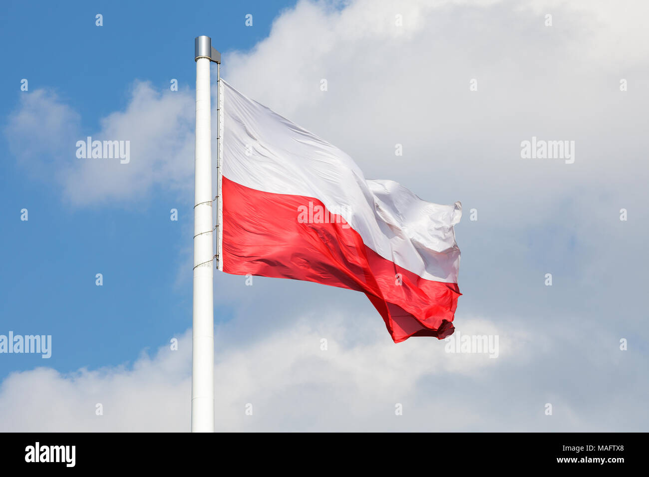 Nazionale Polacca di bandiera sventola sul vento contro blu cielo molto nuvoloso Foto Stock