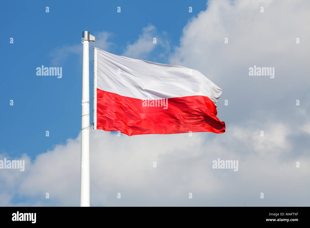 Nazionale Polacca di bandiera sventola sul vento contro blu cielo molto nuvoloso Foto Stock