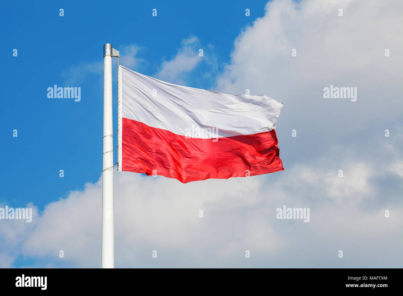 Nazionale Polacca di bandiera sventola sul vento contro blu cielo molto nuvoloso Foto Stock