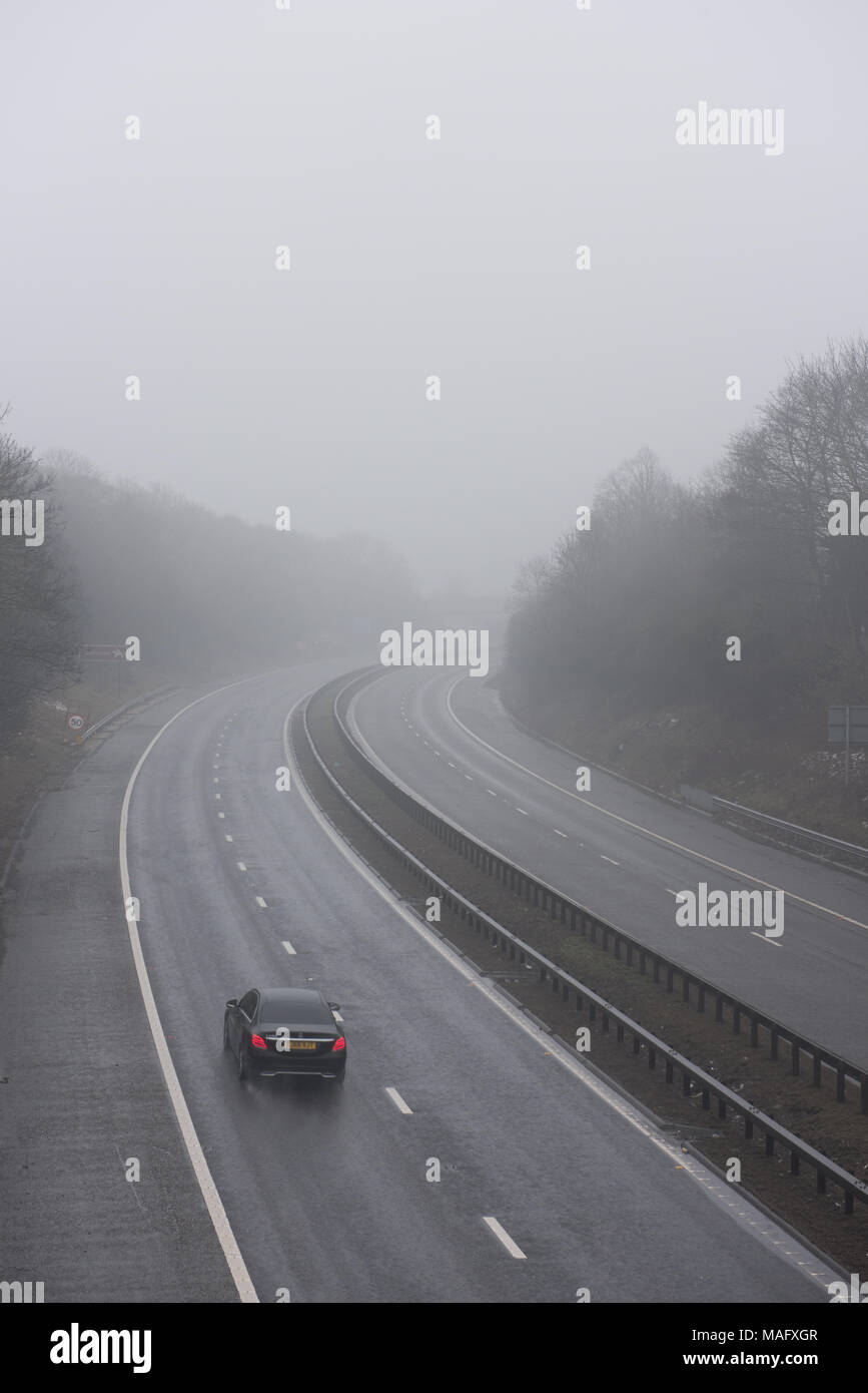 Autocarri e veicoli che percorrono un'autostrada britannica bagnata e nebbiosa, circondata da boschi. Condizioni meteorologiche tipiche del Regno Unito Foto Stock
