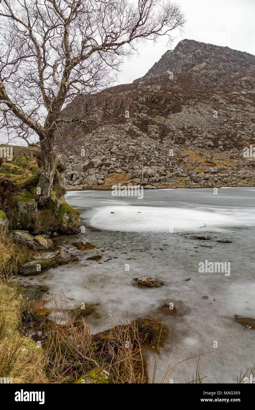 Congelati Ogwen Llyn e penna yr Ole Wen montagna in Snowdonia, il Galles del Nord Foto Stock