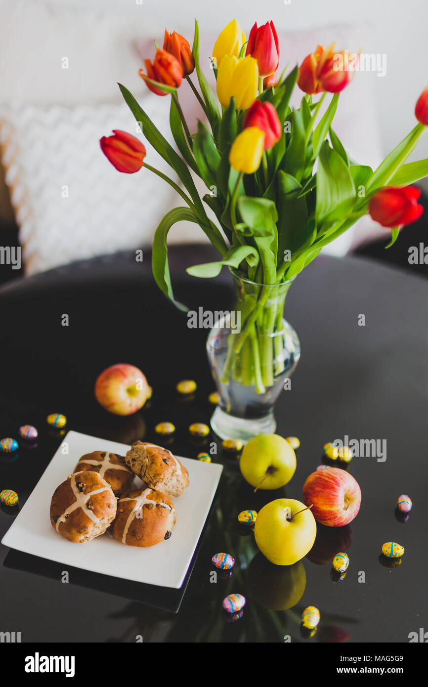 Dolci tradizionali e di uova di cioccolato accanto alle mele e fiori sulla piscina Pasqua Impostazione tabella Foto Stock