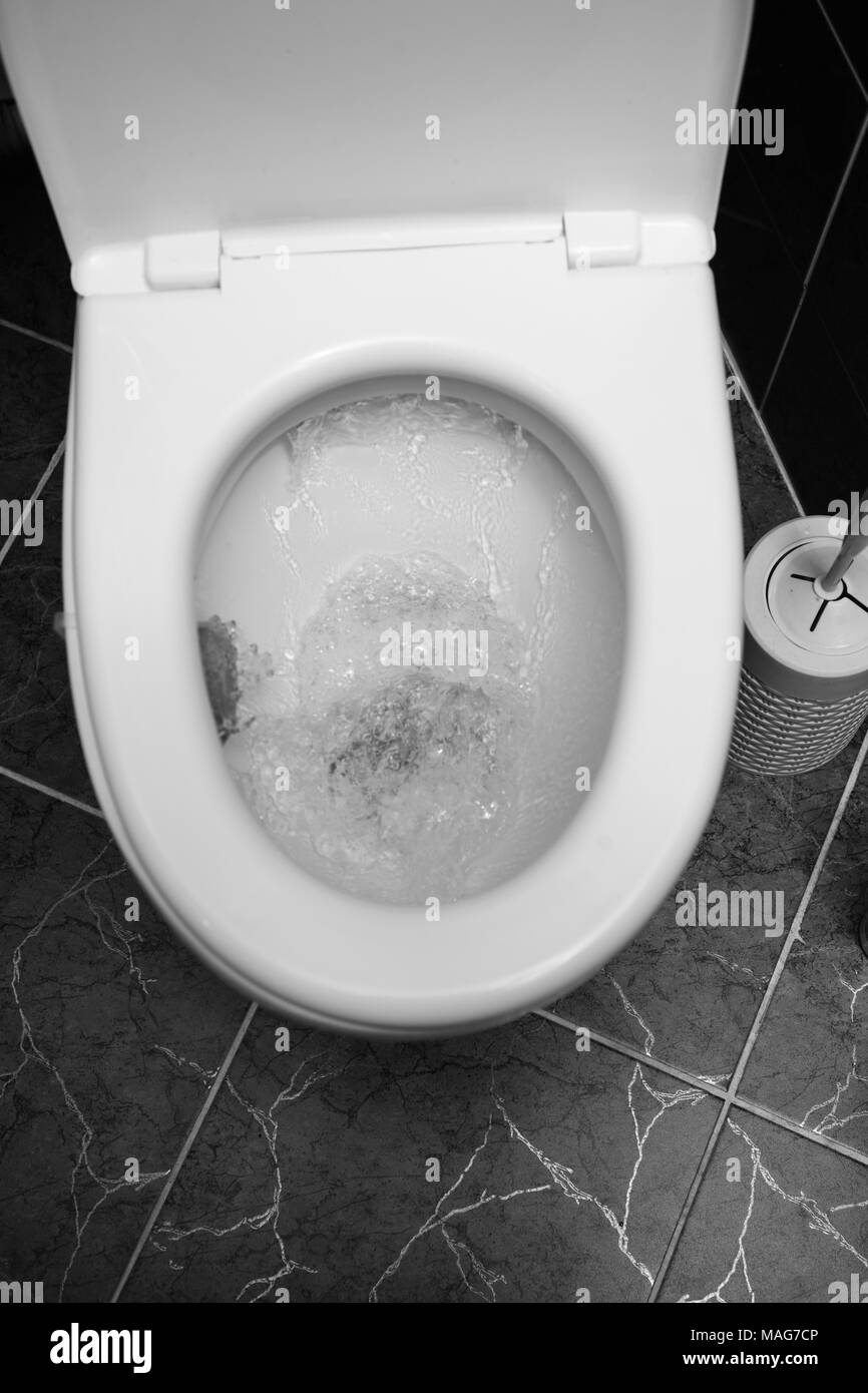 Vista ingrandita di un bianco di lavaggio wc. L'acqua volute nella tazza di gabinetto. Foto Stock
