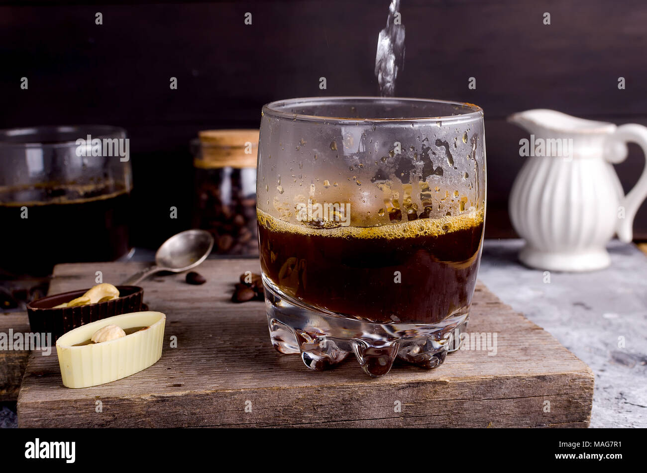 Versando acqua bollente in un bicchiere di caffè al cioccolato e caramelle i grani di caffè latte preparazione Foto Stock