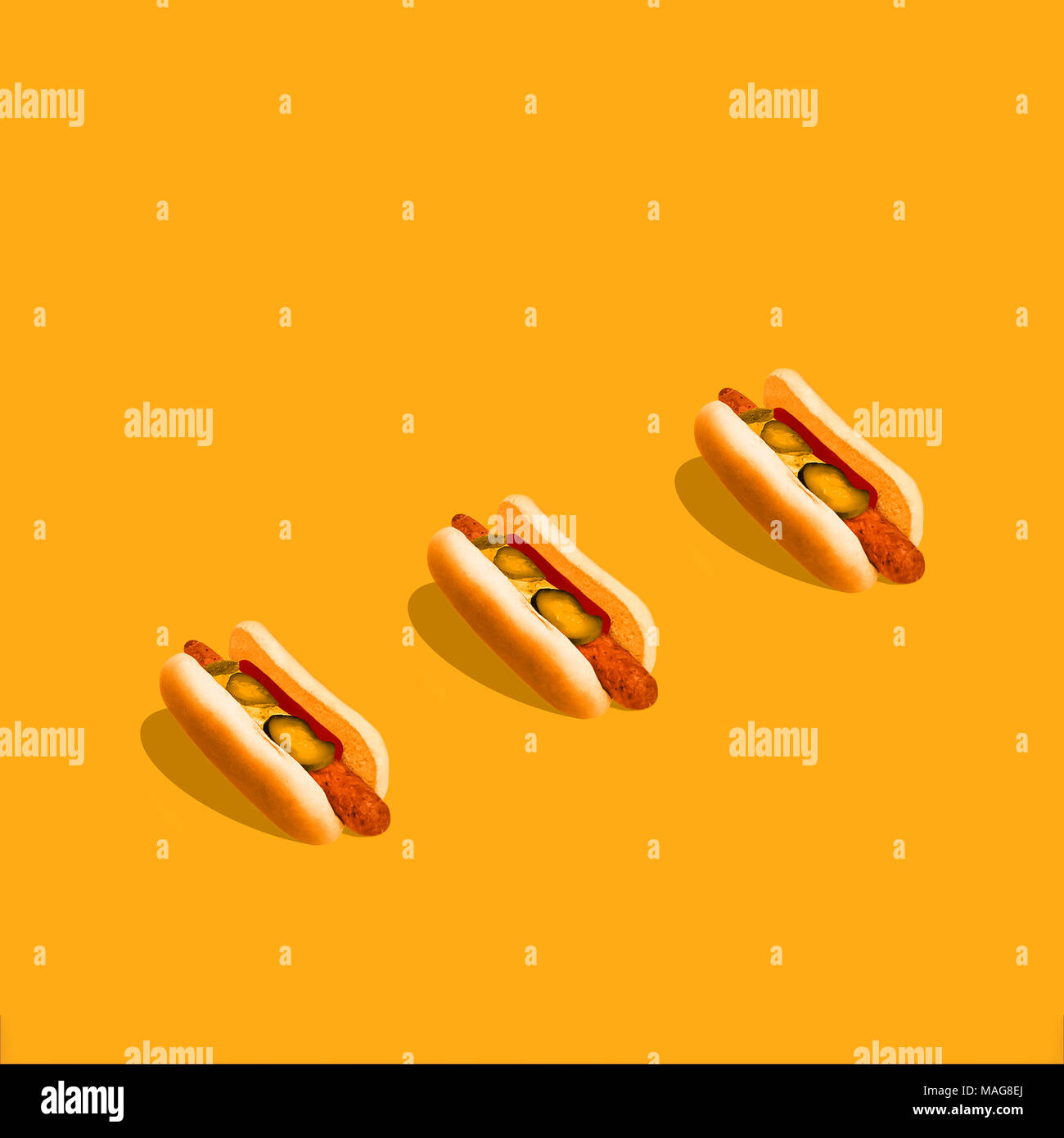 Hot Dog tre hot dog con senape e cetrioli sottaceto sono giacenti su di colore giallo brillante background mockup alla moda per poster e insegne con spazio di copia Foto Stock