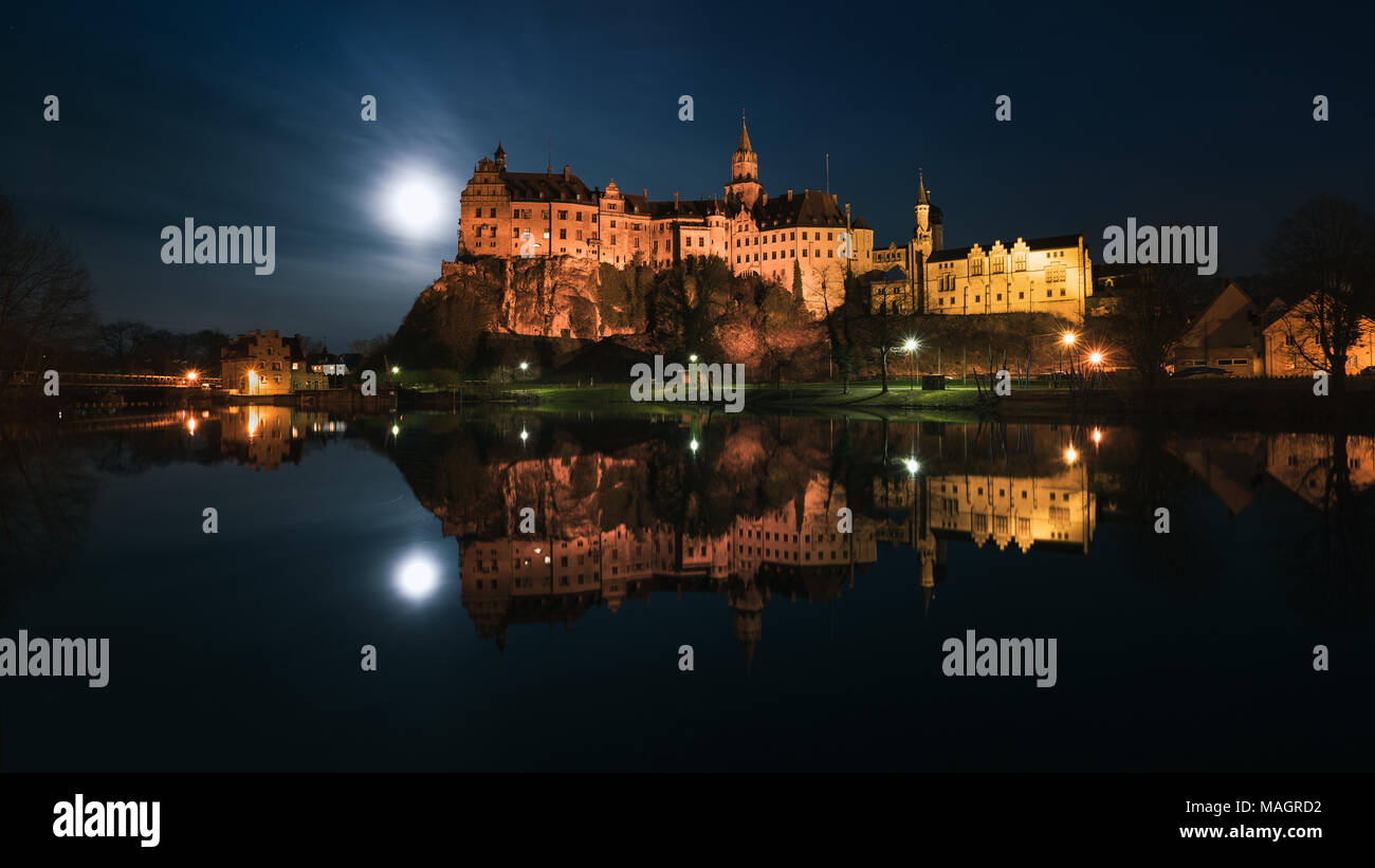 Il Castello Hohenzollern di Sigmaringen è situato direttamente sul Danubio, la luna piena accanto al castello si illumina le frazioni. Foto Stock