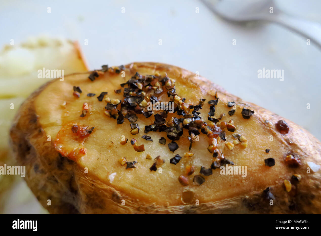 Un patate al forno tagliare piatta con grossolana del pepe su di esso. Foto Stock