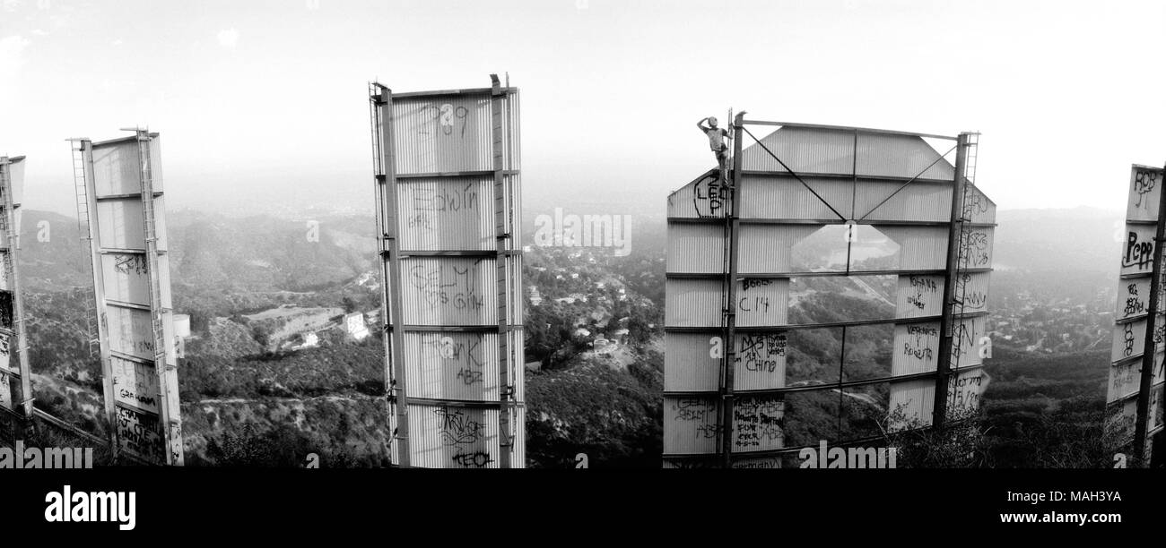 Un uomo si arrampica il segno di Hollywood per una vista di Los Angeles, California. Foto Stock