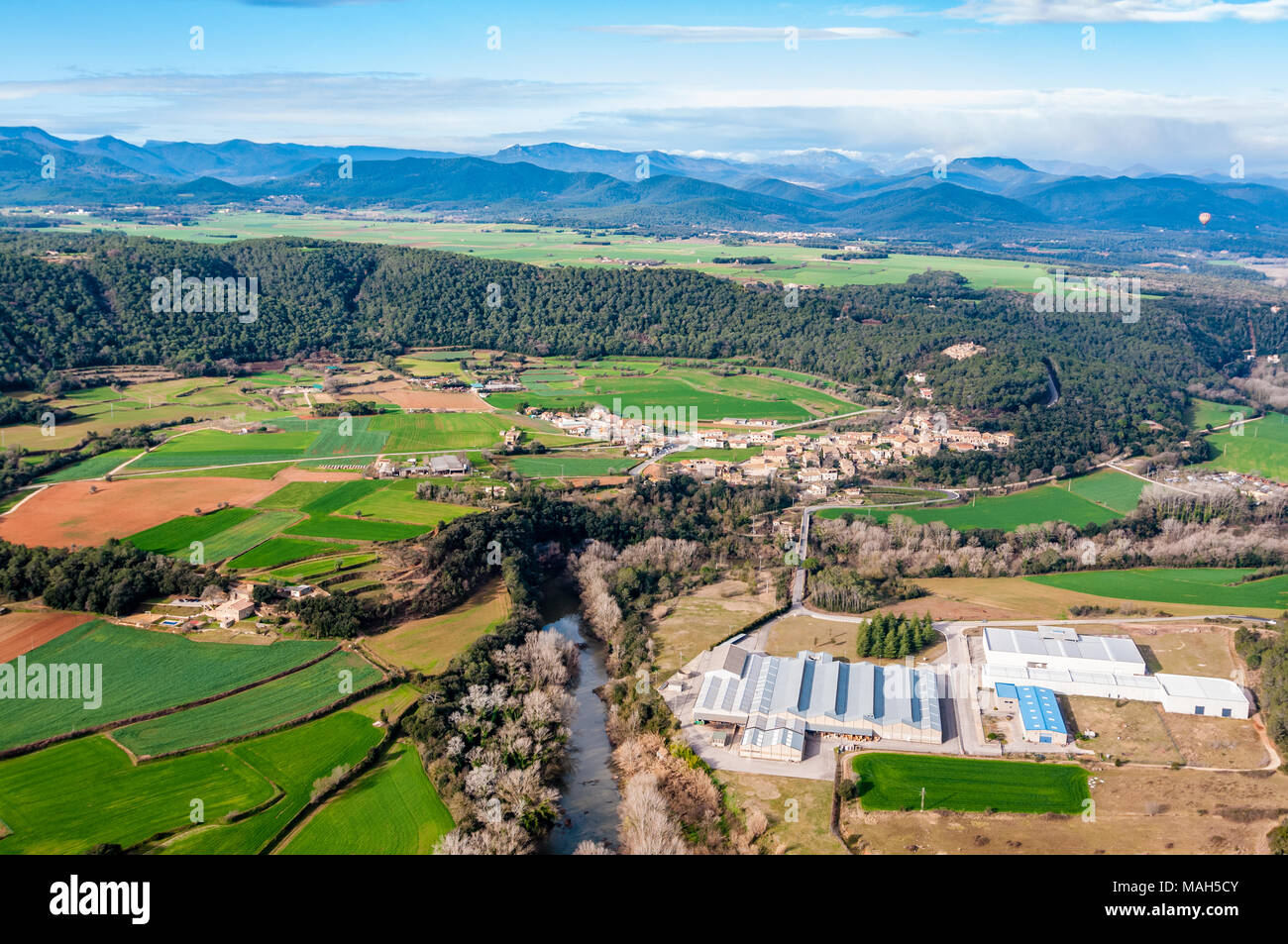 Vista aerea di campi di raccolto e parco industriale con tubicini di foresta, alcune noci sulla destra, Garrotxa, Catalogna, Spagna Foto Stock