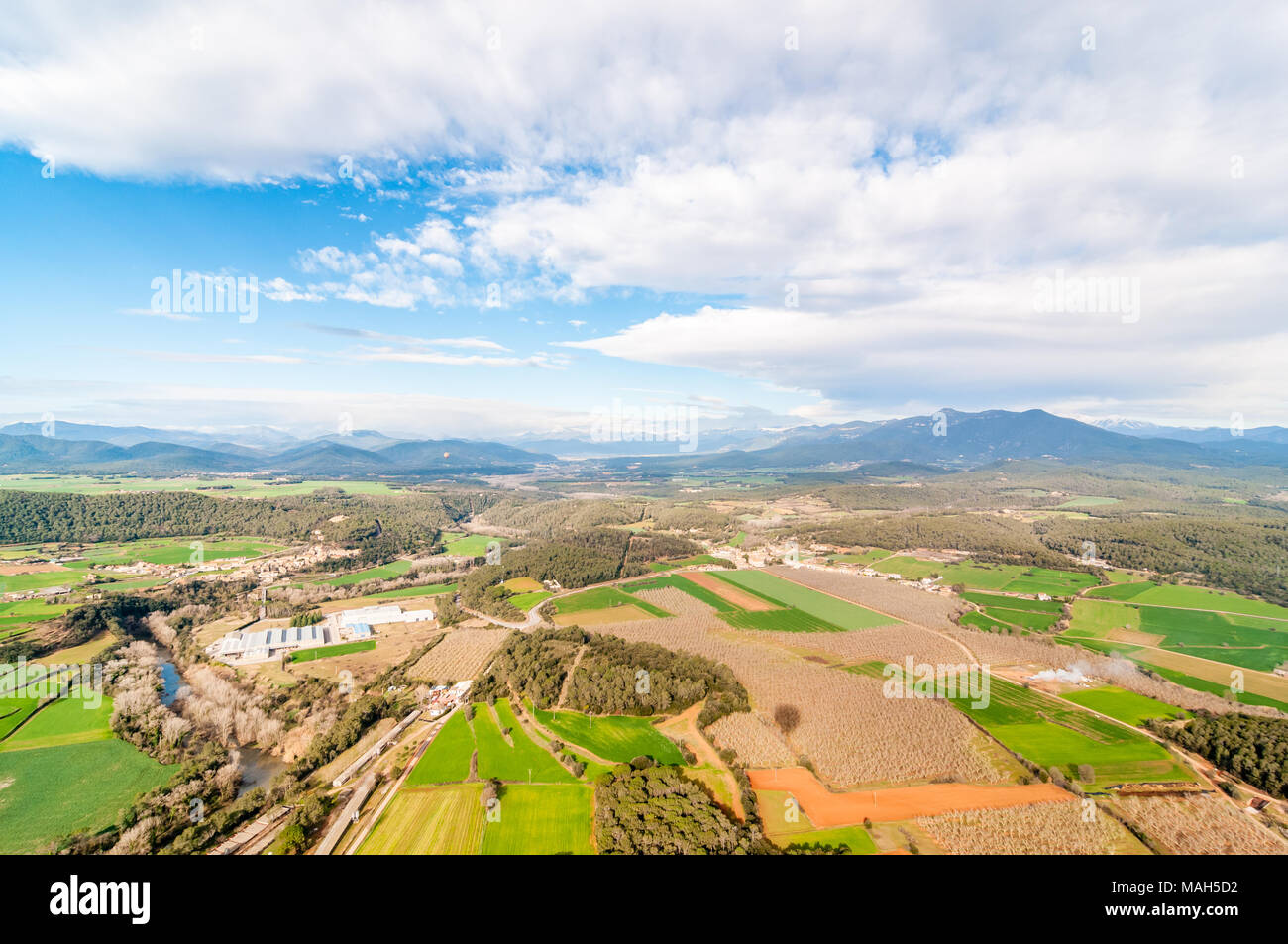 Vista aerea di campi di raccolto e la zona industriale con la foresta tubicini, alcune noci sulla destra, Garrotxa, Catalogna, Spagna Foto Stock