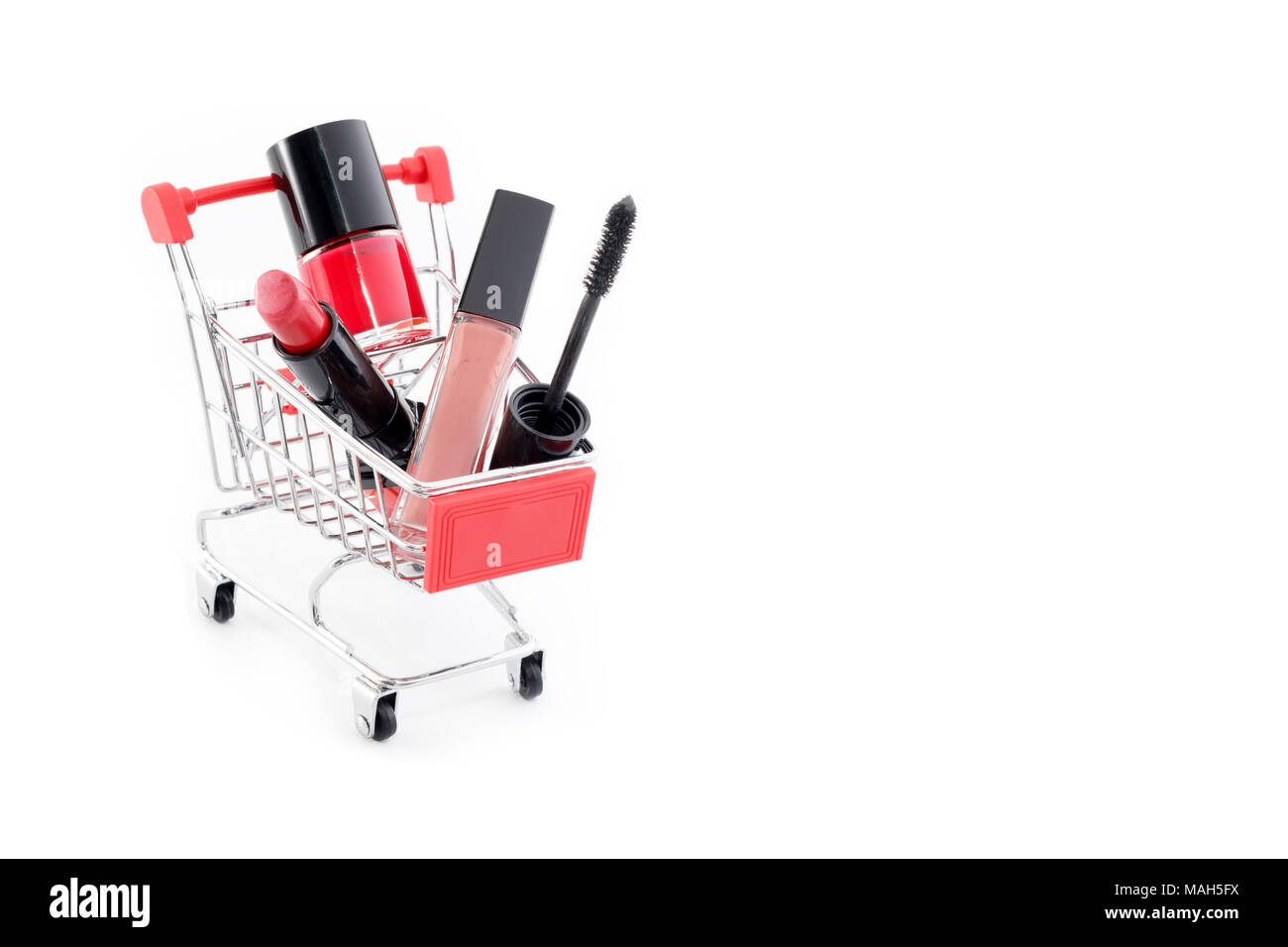 Trucco nella pushcart isolati su sfondo bianco. Rossetto rosso, mascara, rosa lip gloss, polvere, smalto per unghie. Prodotti per il trucco nel carrello, sconto o vendita del tema. Devono haves e bellezza preferiti Foto Stock