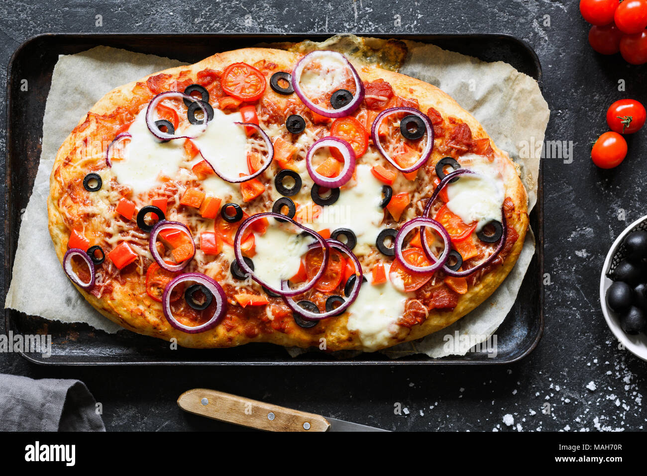 La pizza fatta in casa con olive nere, cipolla, salsa di pomodoro, pepe e  formaggio sulla placca da forno. Vista superiore Foto stock - Alamy