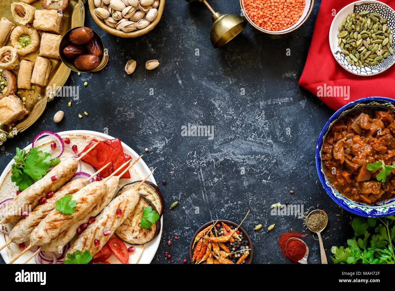 Bagno turco o cucina araba. Cibo turco sulla pietra scura sullo sfondo, vista dall'alto con copia spazio per il testo. Kebab, baklava, imam bayildi, spezie e dadi Foto Stock