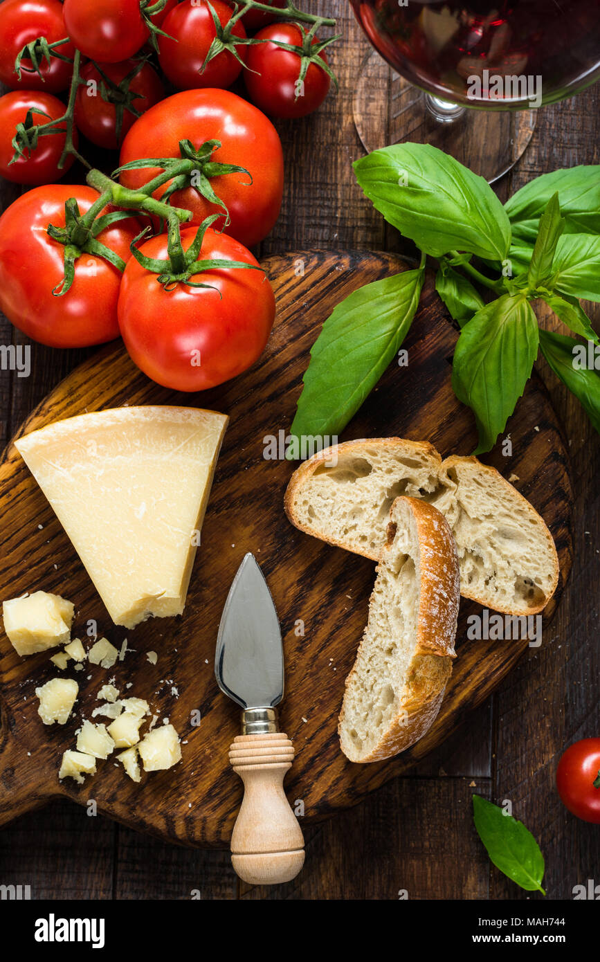 Il formaggio parmigiano reggiano, ciabatta, basilico, di pomodori freschi e un bicchiere di vino rosso. Cucina Italiana Cucina Italiana. Vista superiore Foto Stock