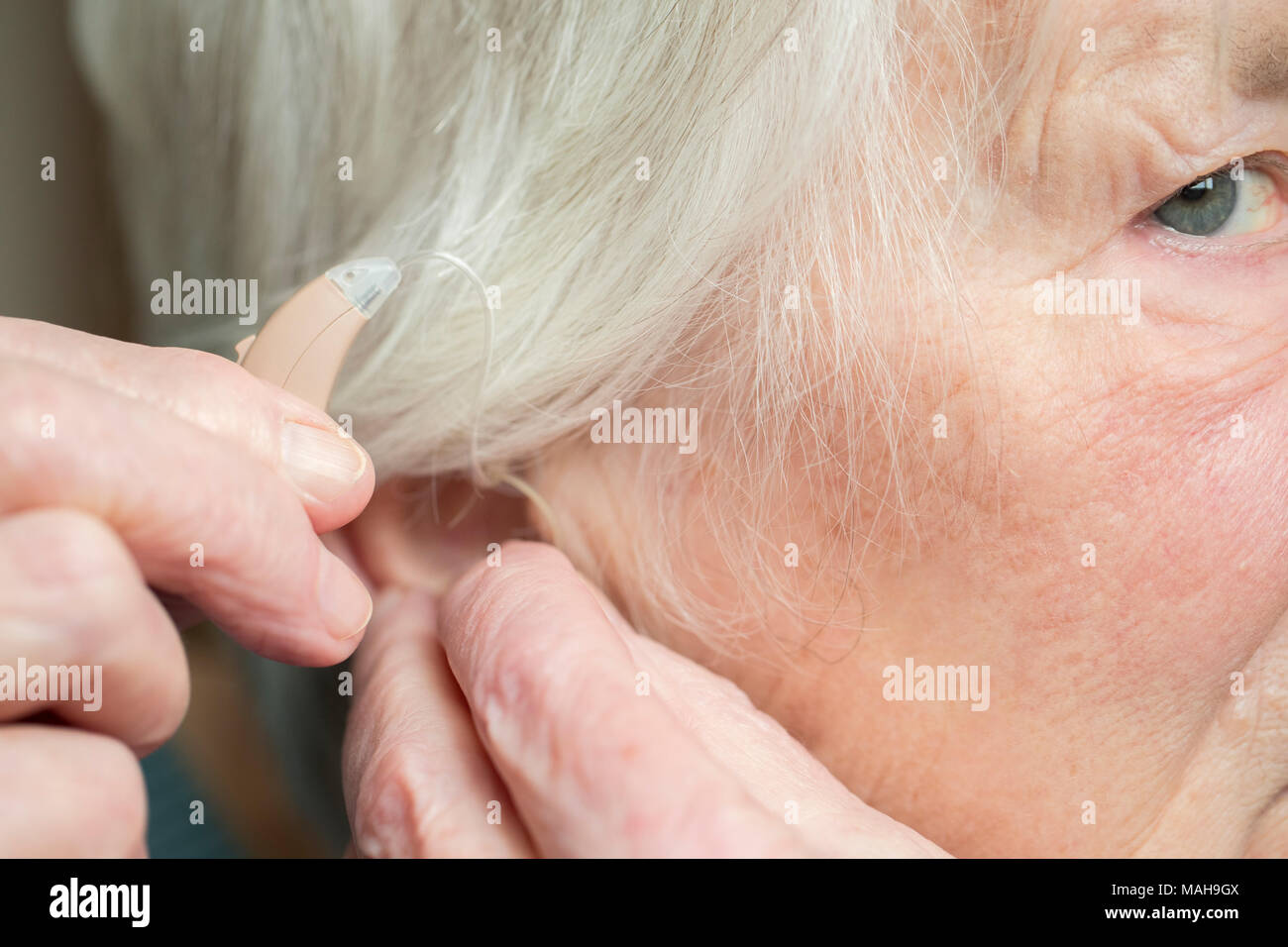 Close Up di Senior donna mettendo in aiuto dell'udito Foto Stock