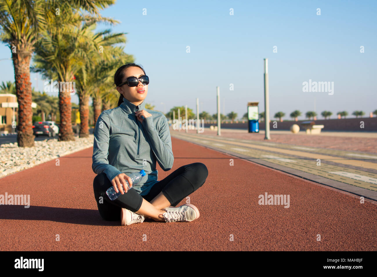 Ragazza seduta su una via di corsa e prendendo una pausa da allenamento Foto Stock