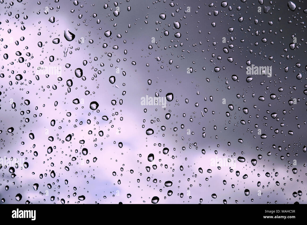 Gocce di pioggia su un vetro contro le nuvole di tempesta Foto Stock