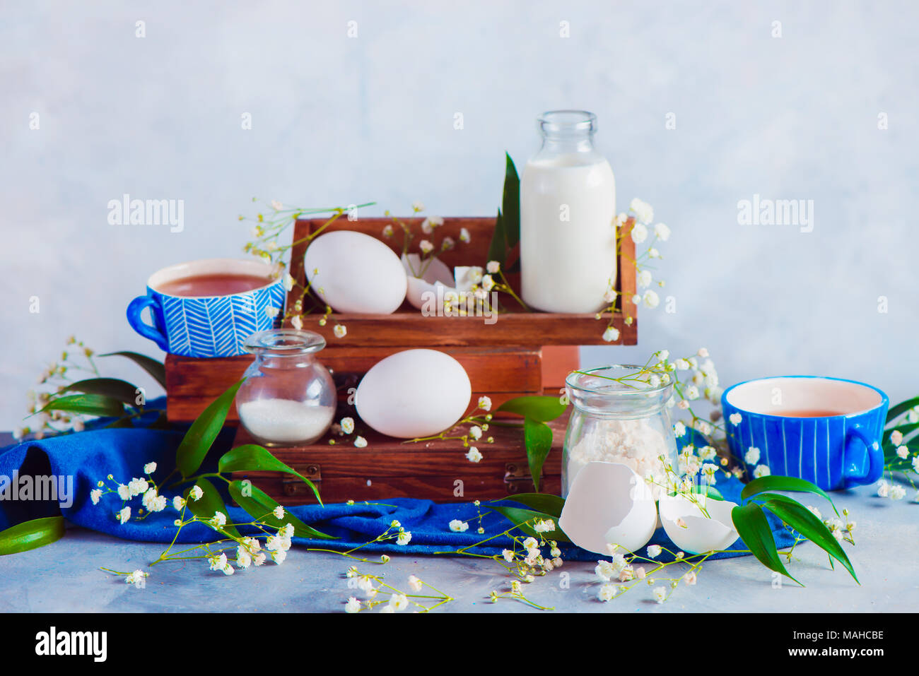 Molla di fotografia alimentare con gypsophila fiori. Home concetto di cucina a vista con cottura ingredienti, le uova, il latte, la farina su uno sfondo luminoso. Foto Stock