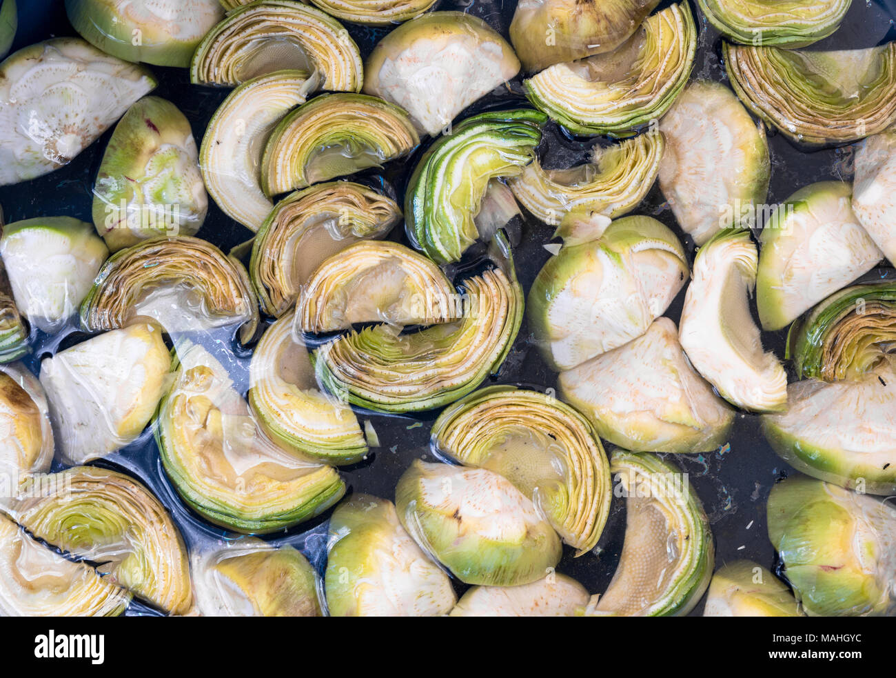 Tagliare i carciofi in acqua sul mercato in stallo. Verde ortaggi sani. Foto Stock