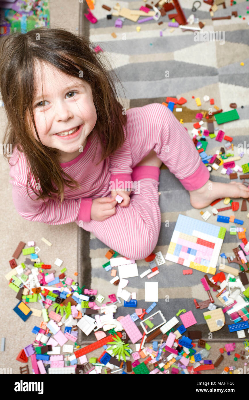 Giovane ragazza sorridente giocando con lego guardando la fotocamera Foto Stock