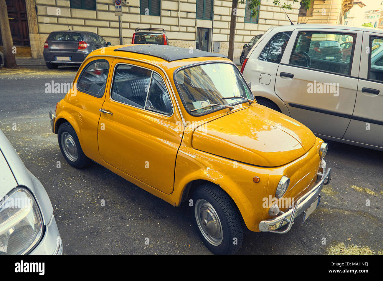 Piccolo giallo auto retrò tra auto moderne per le strade di Roma, Italia Foto Stock