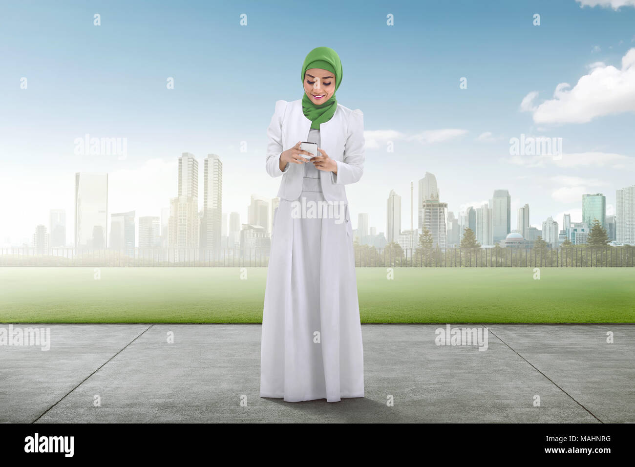 Sorridente musulmani asiatici donna con cellulare sul parco della città Foto Stock