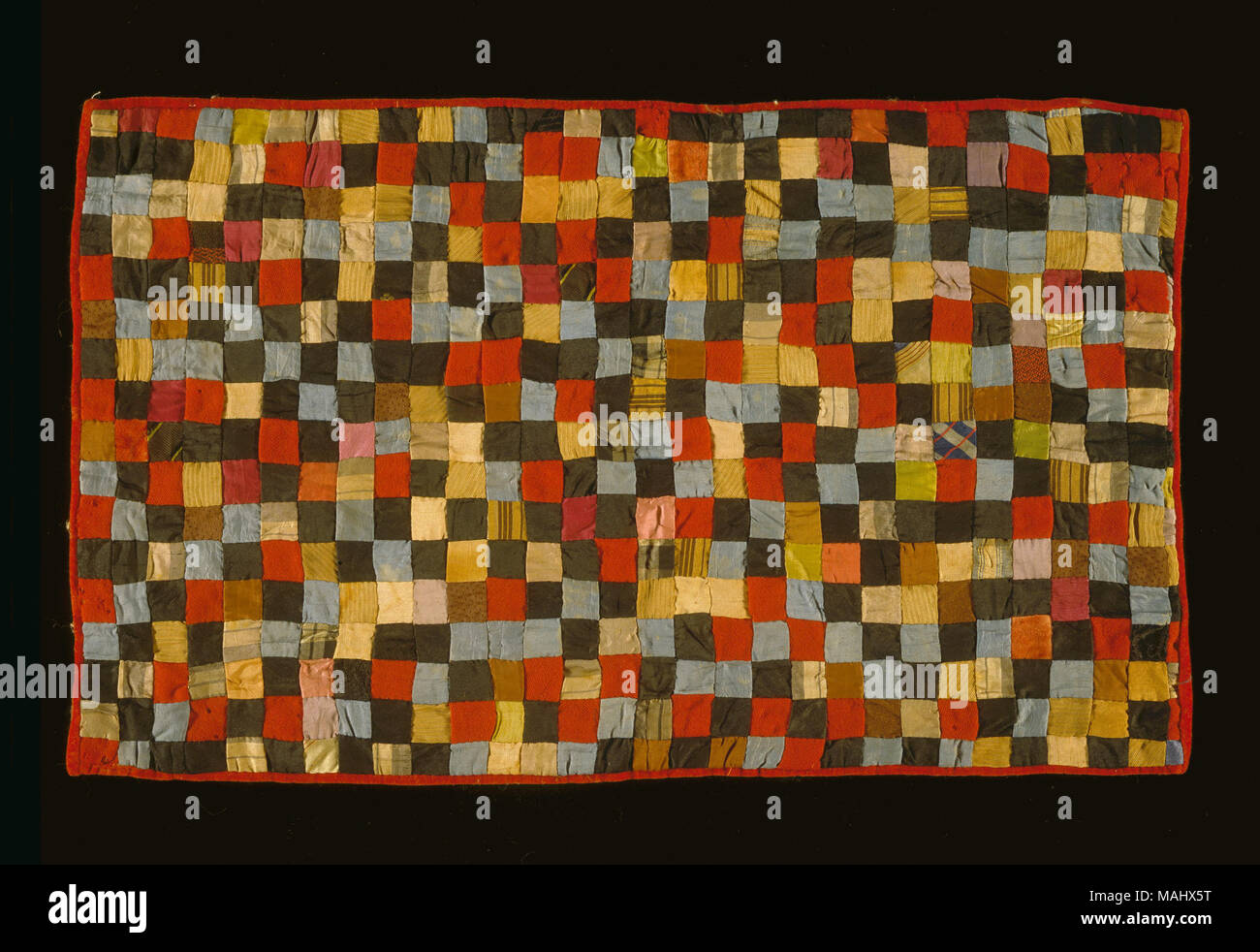 Piccole doll quilt in un multi-colore block pattern con velluto rosso a bordo. Titolo: la bambola Quilt in piccolo blocco Pattern . probabilmente 1900. Foto Stock