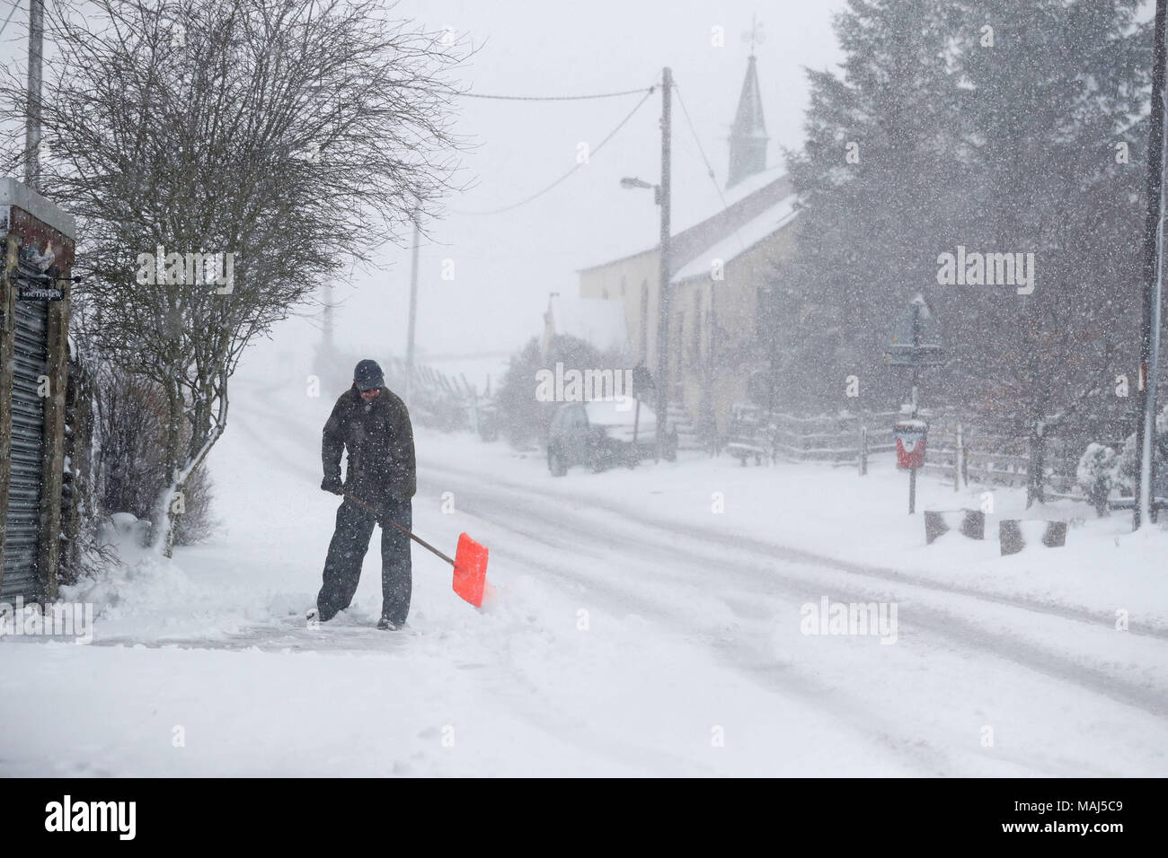 Un uomo si cancella la neve nei pressi della Contea di Durham, come cinque gli avvisi meteo sono in luogo come pioggia e neve batterico fasce del paese il lunedì di Pasqua. Foto Stock