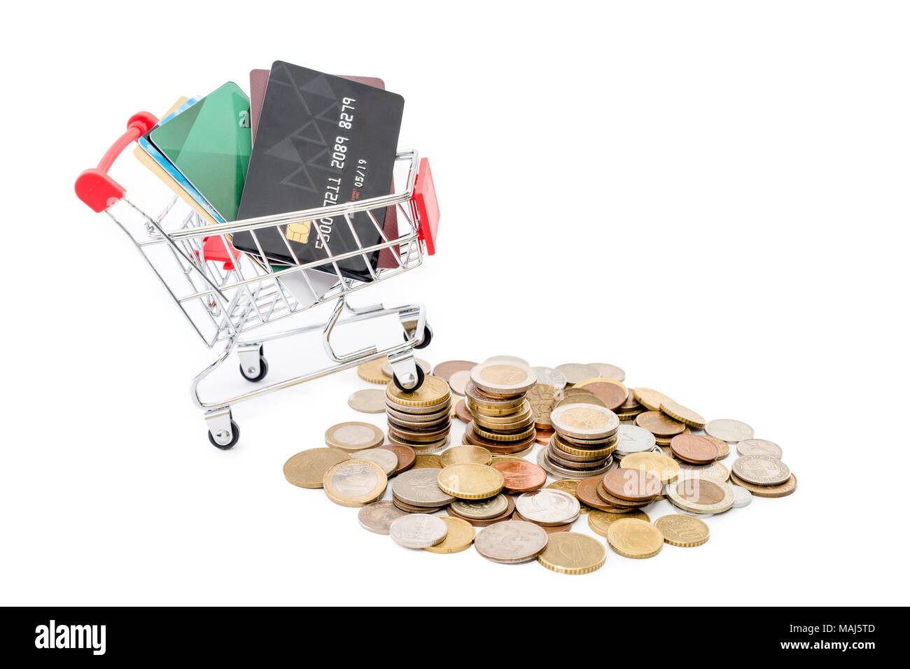 Carrello della spesa con carte di credito è in sella a una pila di monete su sfondo bianco. Foto Stock