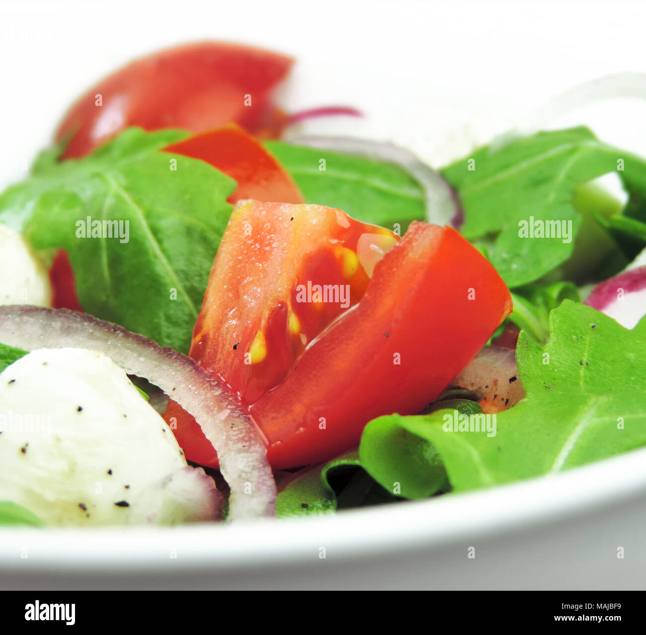 Gourmet o insalata fresca insalata caprese con pomodori, le cipolle rosse, rucola e mozzarella su una piastra bianca. Close-up shot di insalata fresca. Foto Stock