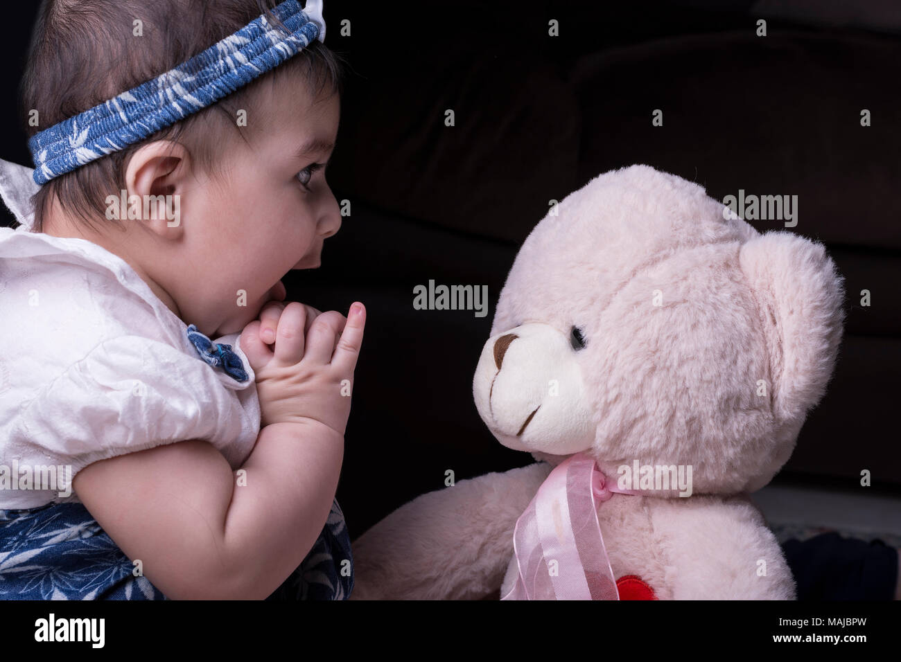 Close up di un adorabile sorpreso bambina gioca con Teddy bear Foto Stock