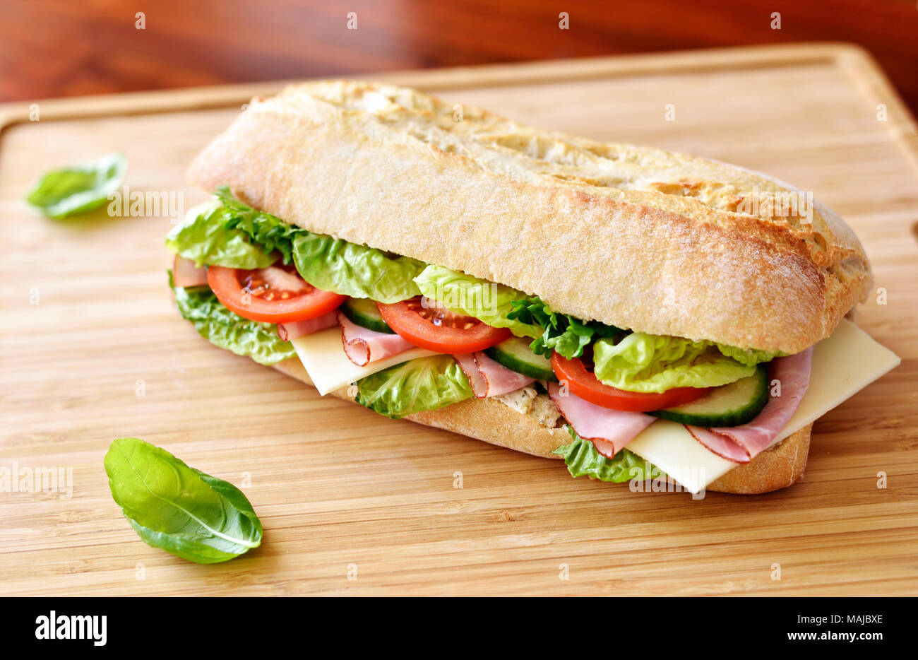 La ciabatta o sandwich club sandwich con ciabatta baguette e vari ingredienti. prosciutto e formaggio baguette con pomodori freschi e insalata. Foto Stock