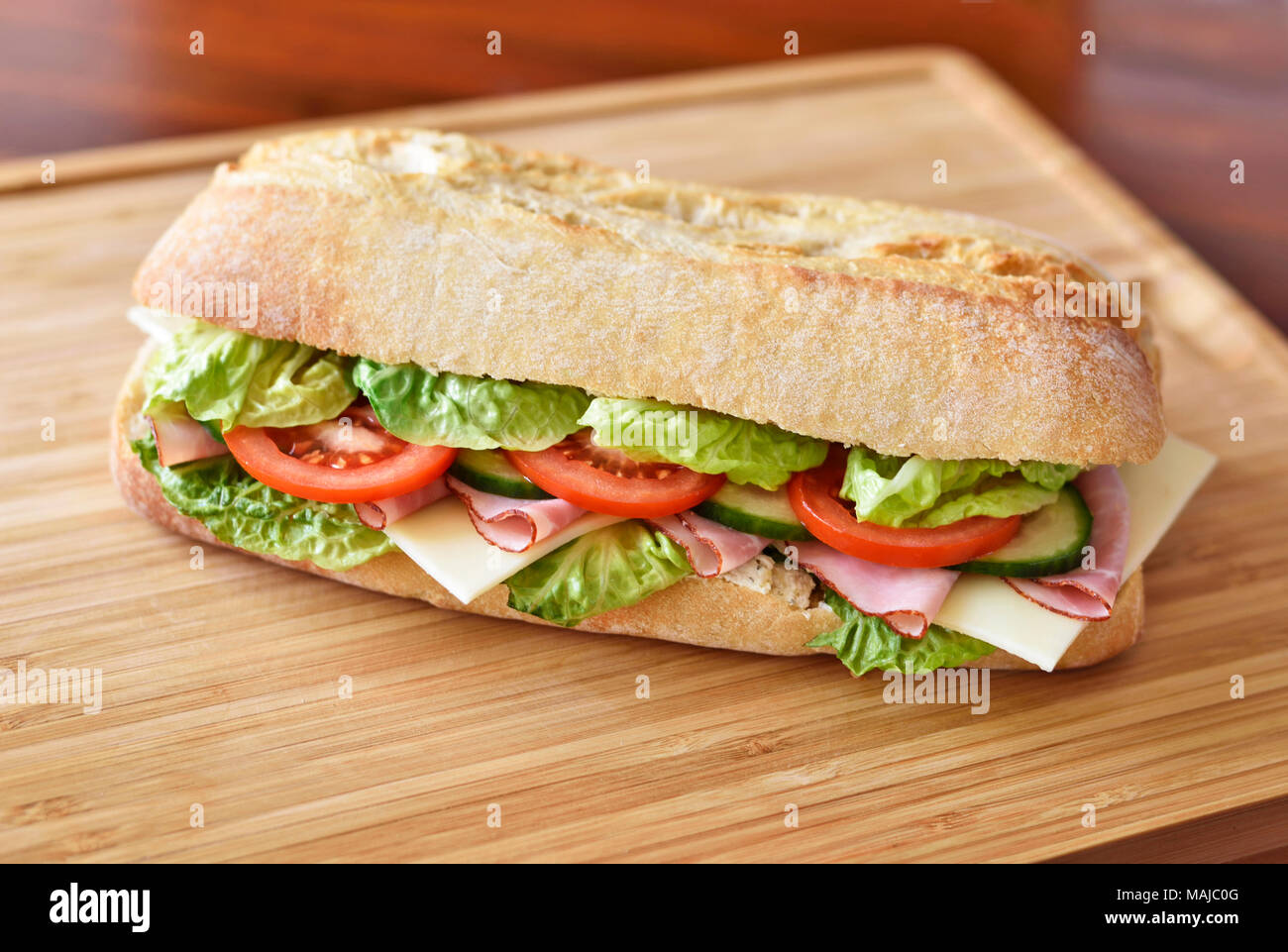 La ciabatta o sandwich club sandwich con ciabatta baguette e vari ingredienti. prosciutto e formaggio baguette con pomodori freschi e insalata. Foto Stock