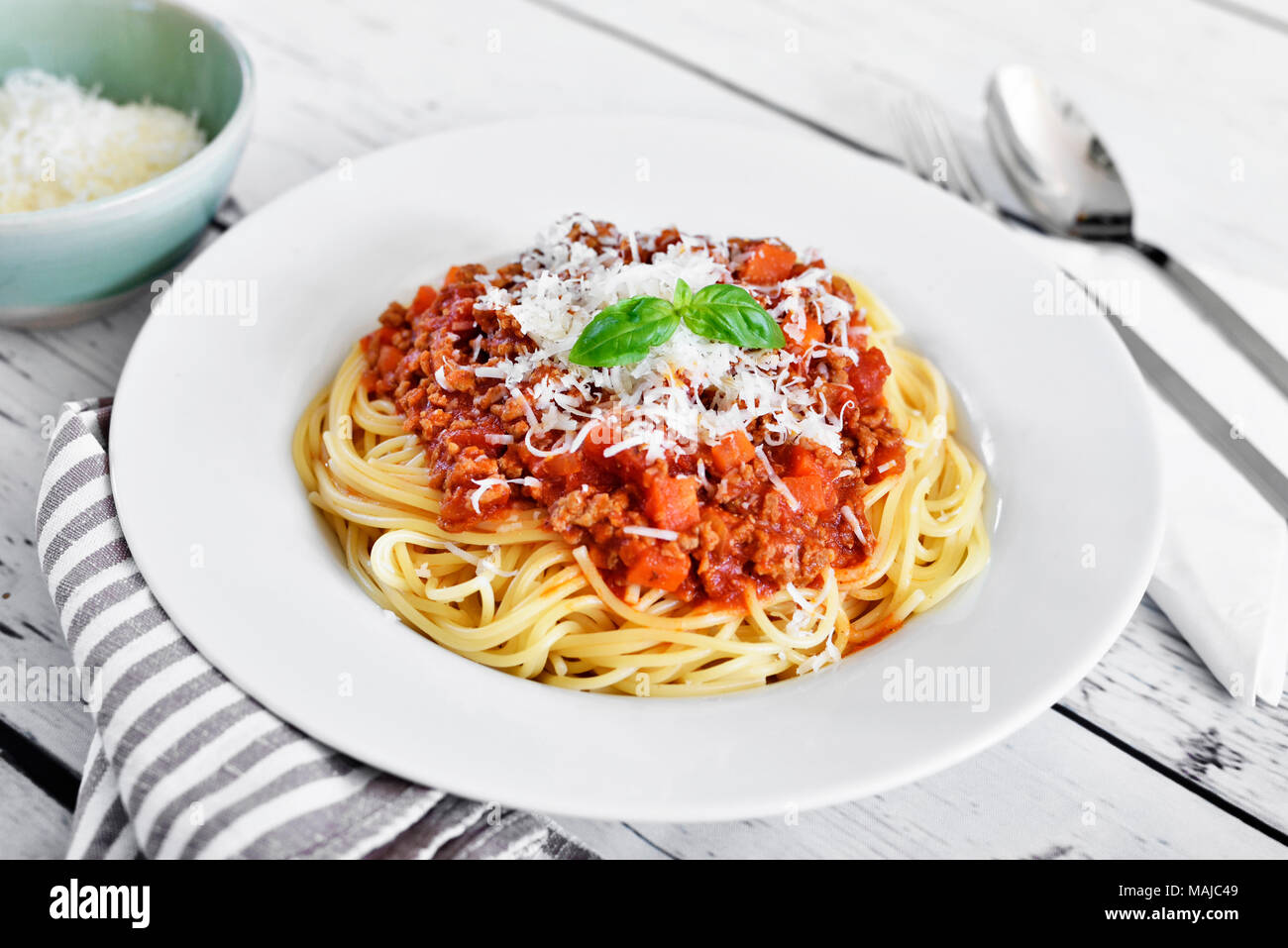 Deliziosa pasta pasto, spaghetti alla bolognese su una piastra bianca. Piatto di pasta, cibo tradizionale italiano con formaggio parmigiano, le carni macinate e le foglie di basilico. Foto Stock