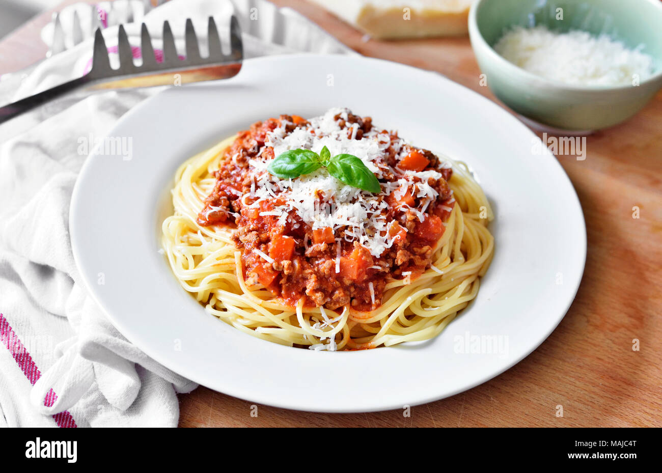 Deliziosa pasta pasto, spaghetti alla bolognese su una piastra bianca. Piatto di pasta, cibo tradizionale italiano con formaggio parmigiano, le carni macinate e le foglie di basilico. Foto Stock