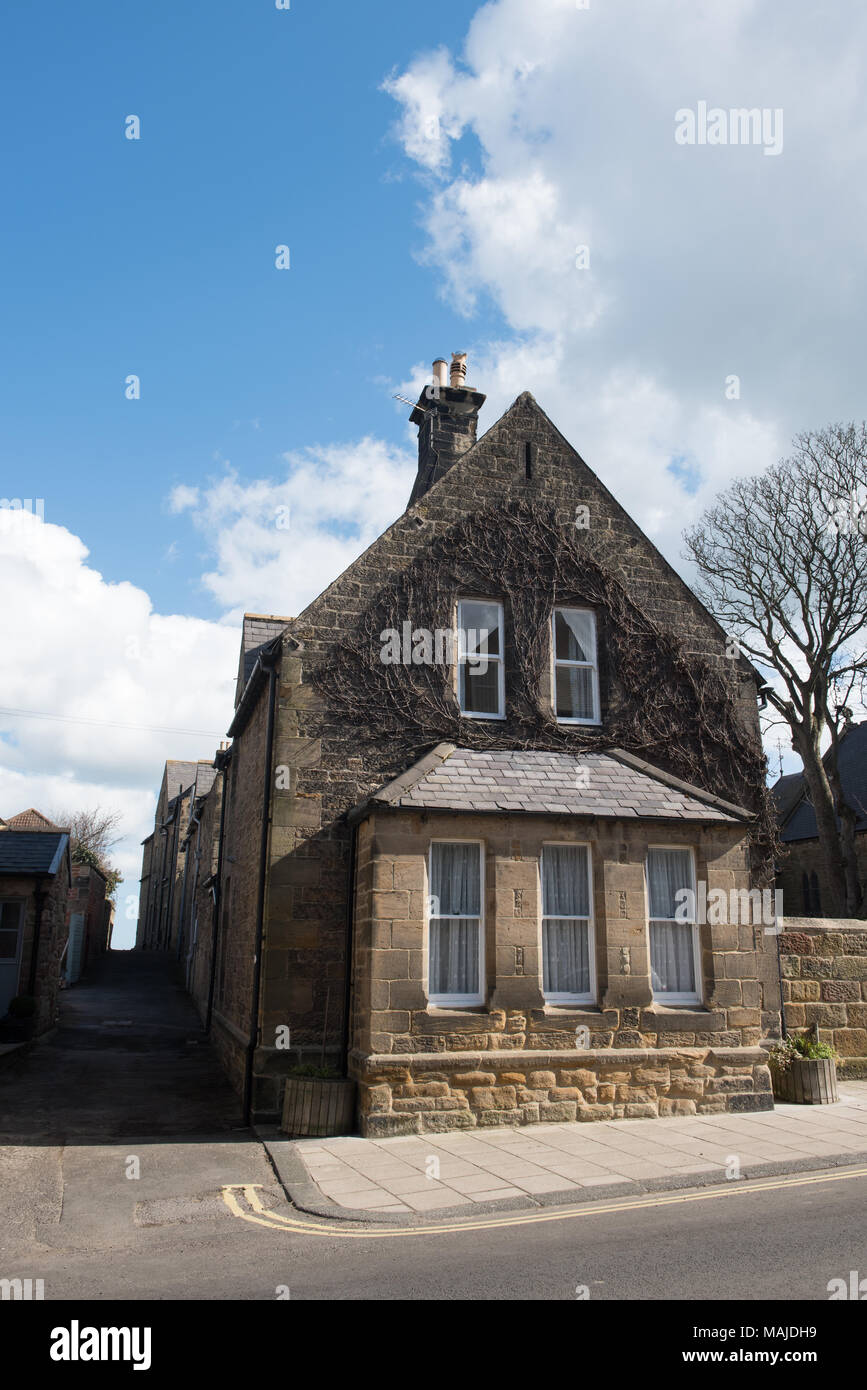 Casa tradizionale in pietra ad Alnmouth, Northumberland, Inghilterra, sotto un cielo blu luminoso con nuvole Foto Stock