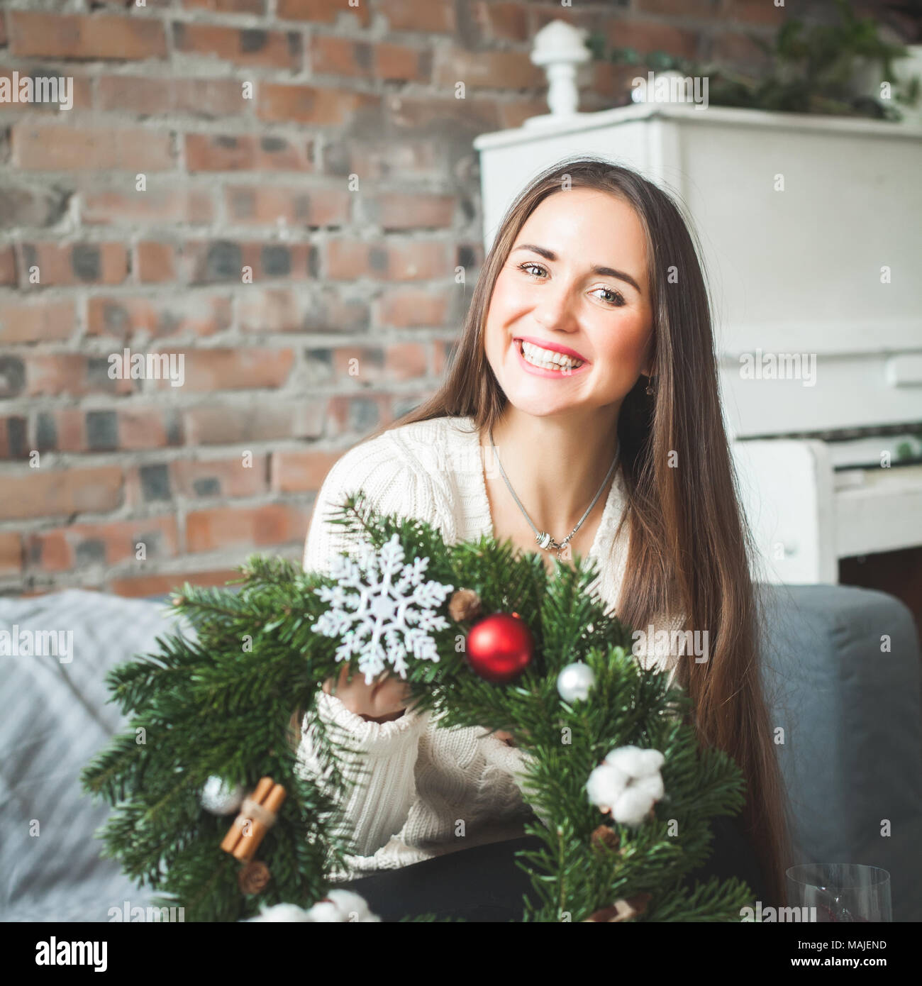 Donna felice con l'inverno Ghirlanda di Natale a casa Foto Stock