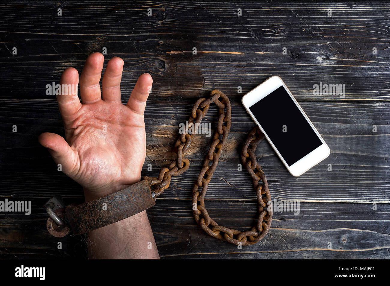 Smart phone addiction concetto su sfondo rosso. La mano viene ammanettato per lo smartphone Foto Stock